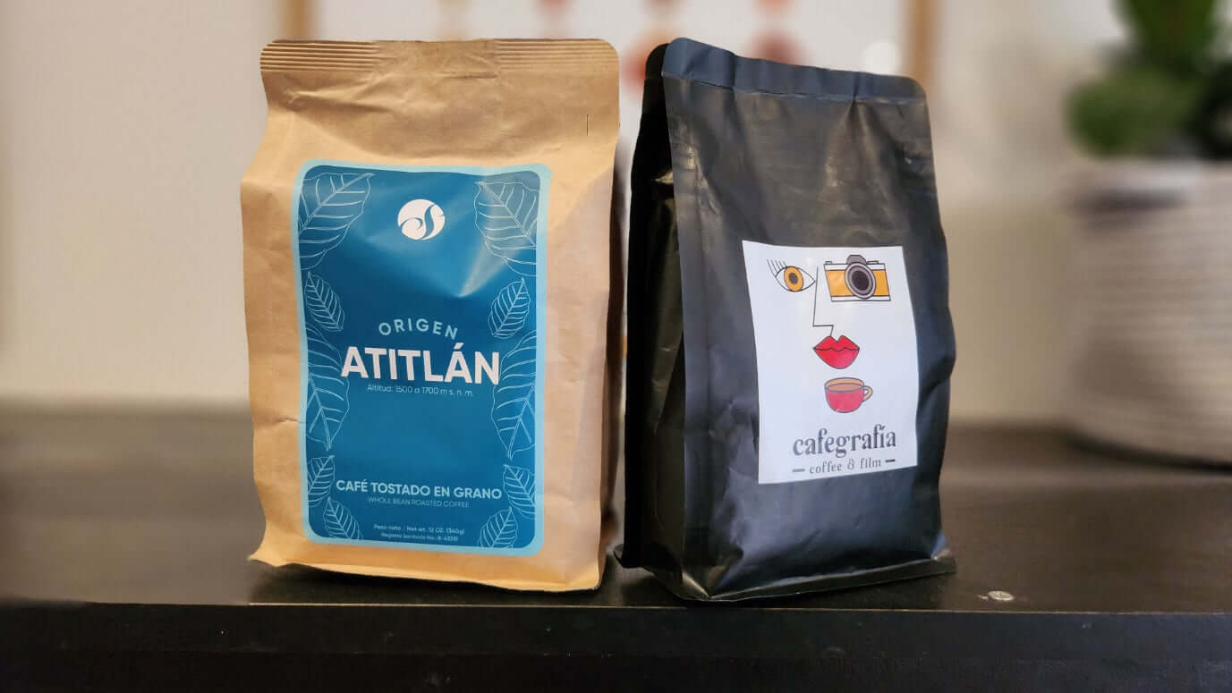 Two specialty coffee bean bags, including Atitlán single origin, on a dark countertop.