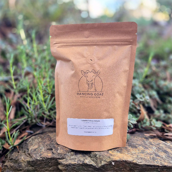 Colombia Galeras Volcano bag of coffee with 'Dancing Goat Coffee' logo on a rock with greenery in the background
